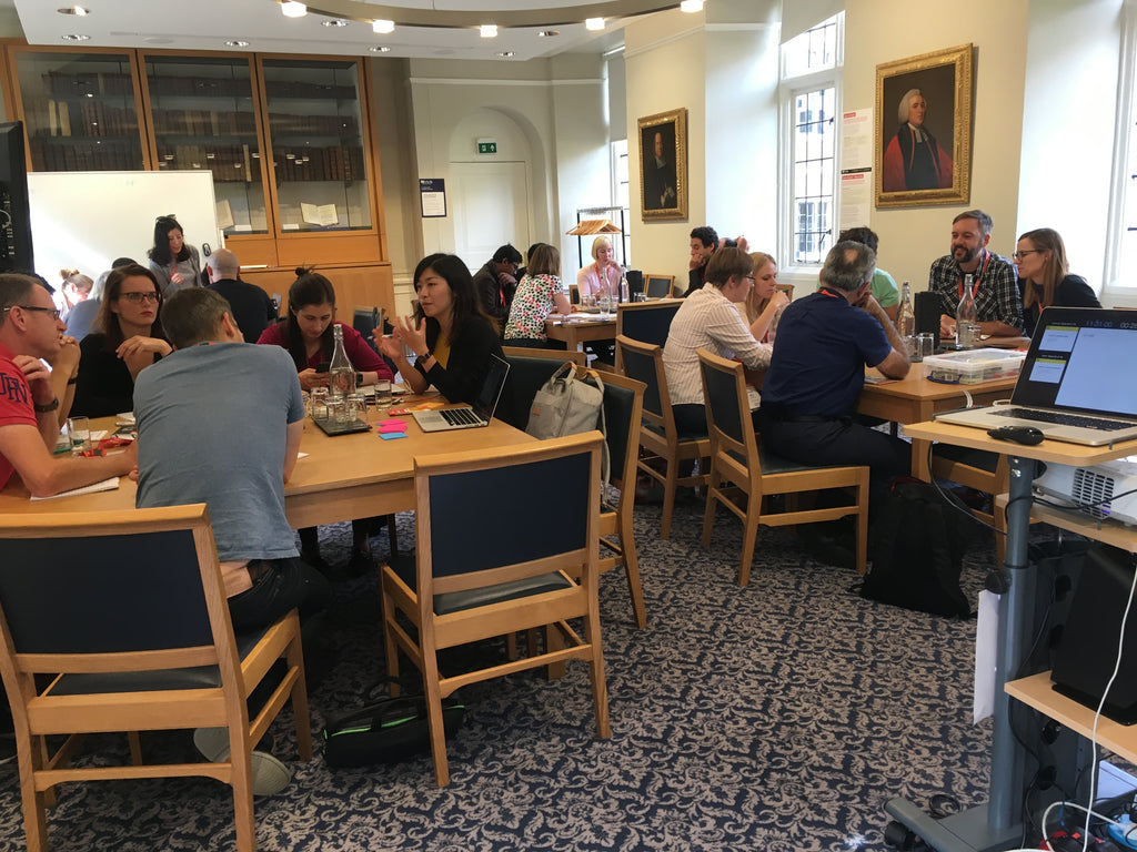Teams grouped around tables during a workshop at UX Cambridge