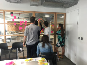 A team of designers discussing ideas on a wall of post it notes