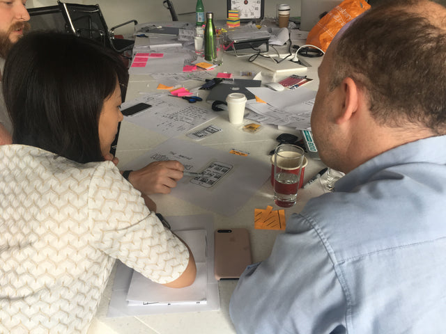 People at a table discussing paper prototypes in a workshop